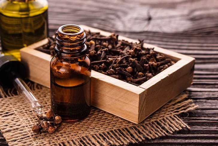 essential oil of cloves on a wooden rustic background.