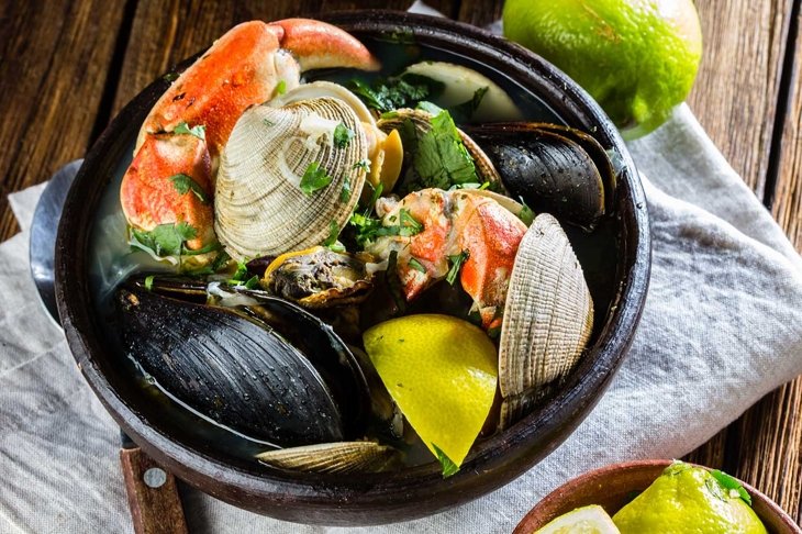 Seafood shellfish soup of mussels, crabs, clams and other shellfish served in clay bowls. typical chilean dish Paila marina or Mariscal. Top view.